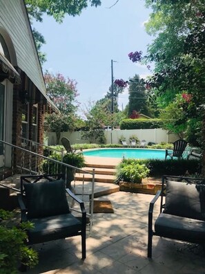 A backyard with a swimming pool, outdoor seating, and a staircase leading to a covered area. - The Brick Cottage - Boat Parking, Close to ATU (Russellville)