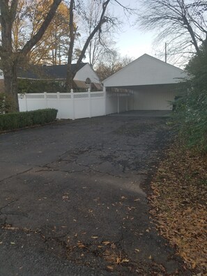 A residential driveway with a garage, a white fence, and leaf-covered ground. - The Brick Cottage - Boat Parking, Close to ATU (Russellville)