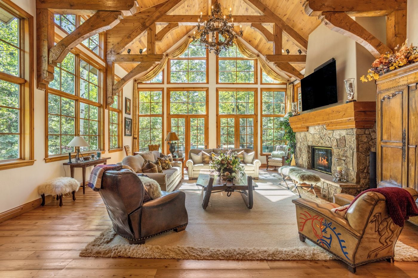 A spacious living room with a fireplace, large windows, and wooden beams.