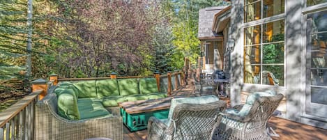 A covered outdoor deck with wicker furniture, a green sofa, and a dining table.