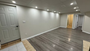 A spacious hallway with a wooden floor, a white door, and recessed ceiling lights. - Cozy,Large 2 Bedroom 1 Bathroom Separate Entrance Basement Apartment in Ancaster (Hamilton)