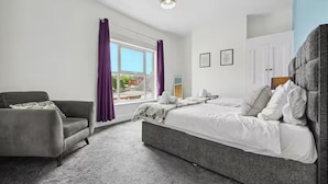 Een slaapkamer met een bed, een stoel en een raam met gordijnen.