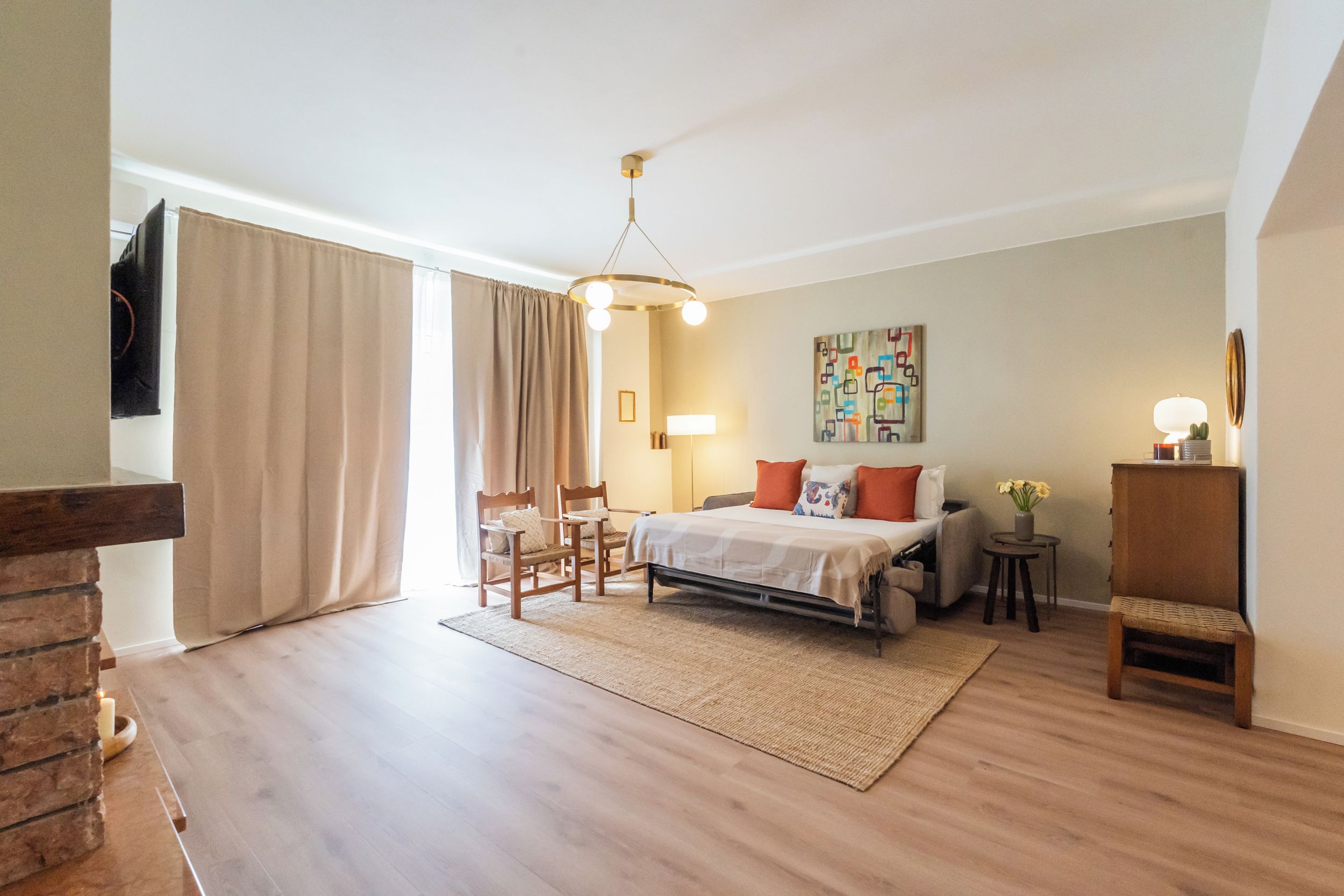 Ein Schlafzimmer mit einem Bett, zwei Stühlen, einem kleinen Tisch, einer Lampe und einem Bild an der Wand.