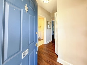 A hallway with a blue door, wooden flooring, and a white wall with a picture. - Luxury 2 bed 2 ba Penthouse - Shelter Cove Marina Views (Hilton Head Island)
