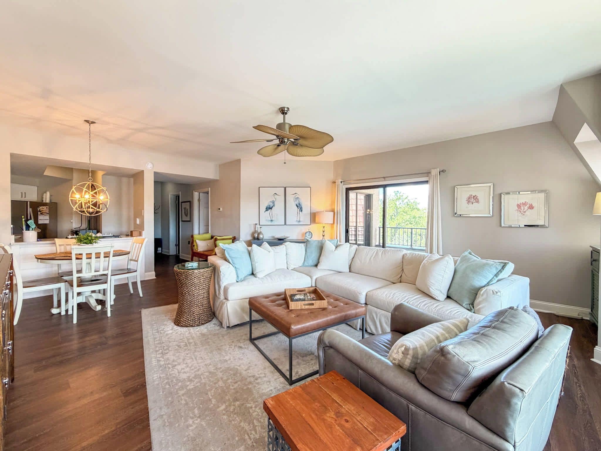 A spacious living room with a large sectional sofa, a coffee table, and a dining area with a chandelier.