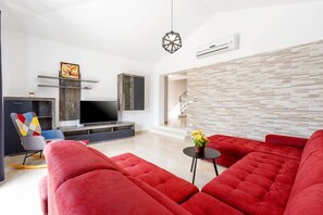 Ein modernes Wohnzimmer mit einer Eckcouch, einem Flachbildfernseher und einer Wanddekoration.