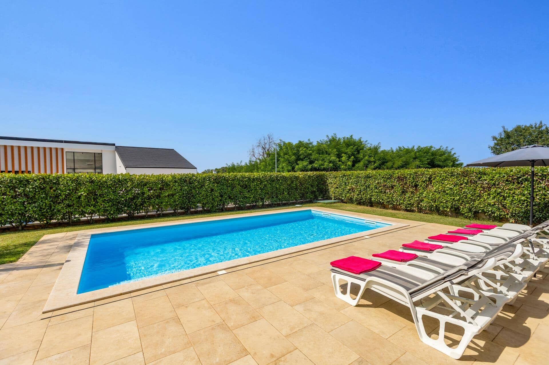 A swimming pool with lounge chairs and a modern building in the background.