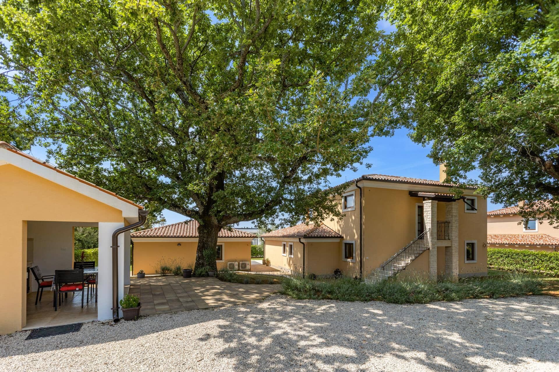 Une cour intérieure avec un bâtiment, un arbre et un espace patio aménagé avec des chaises et une table.