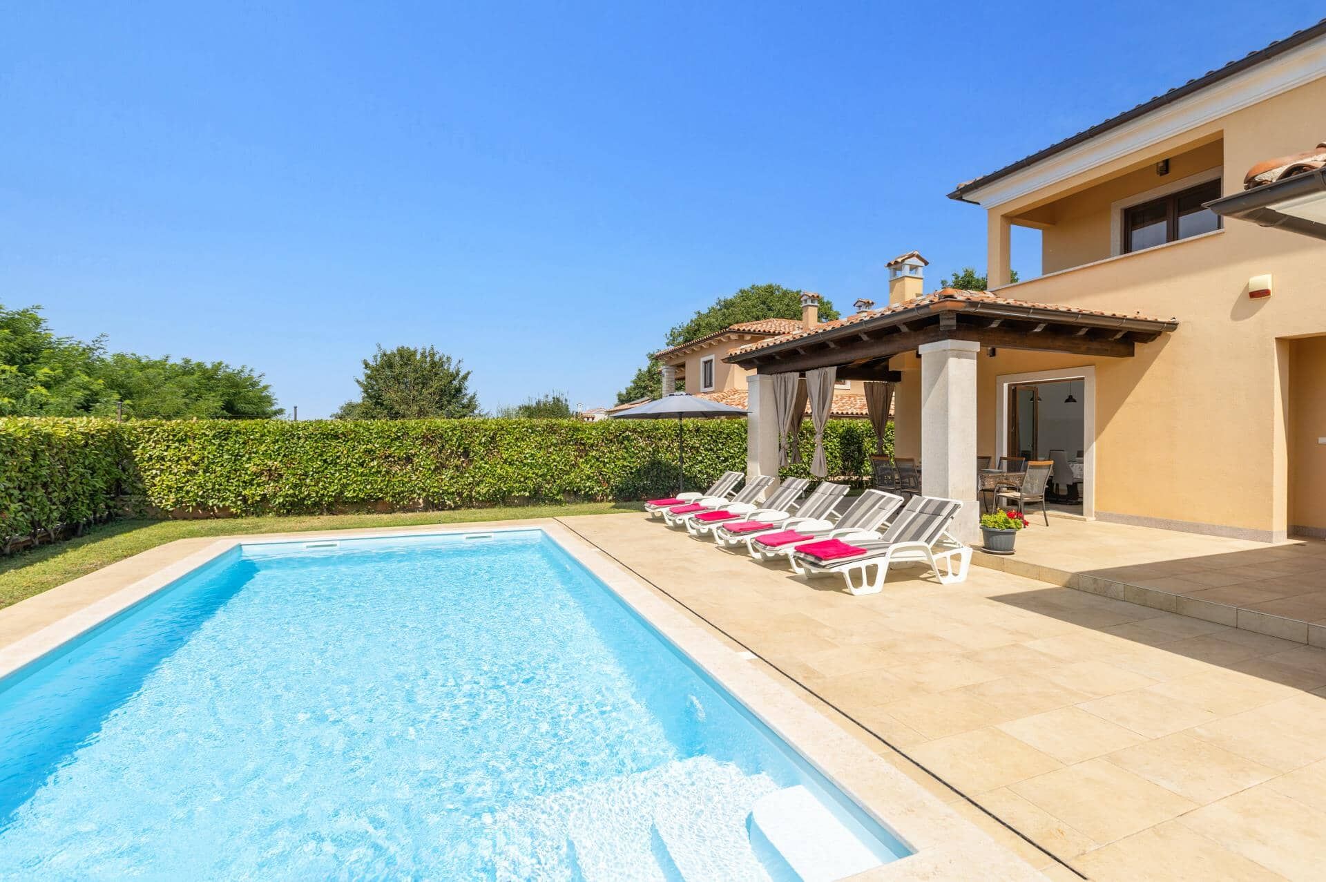 A swimming pool with lounge chairs and a covered patio area.