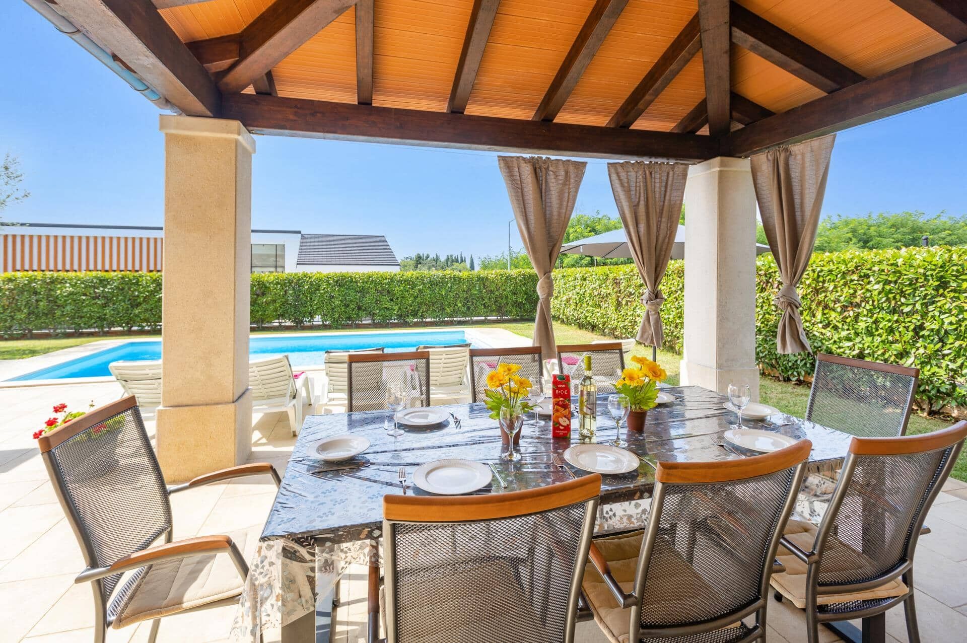 Eine Außenpatio mit Pool, Esstisch, Stühlen und einer Pergola.