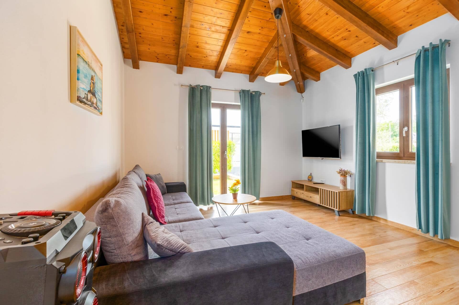 A modern living room with a sofa, a TV, and a wooden ceiling.