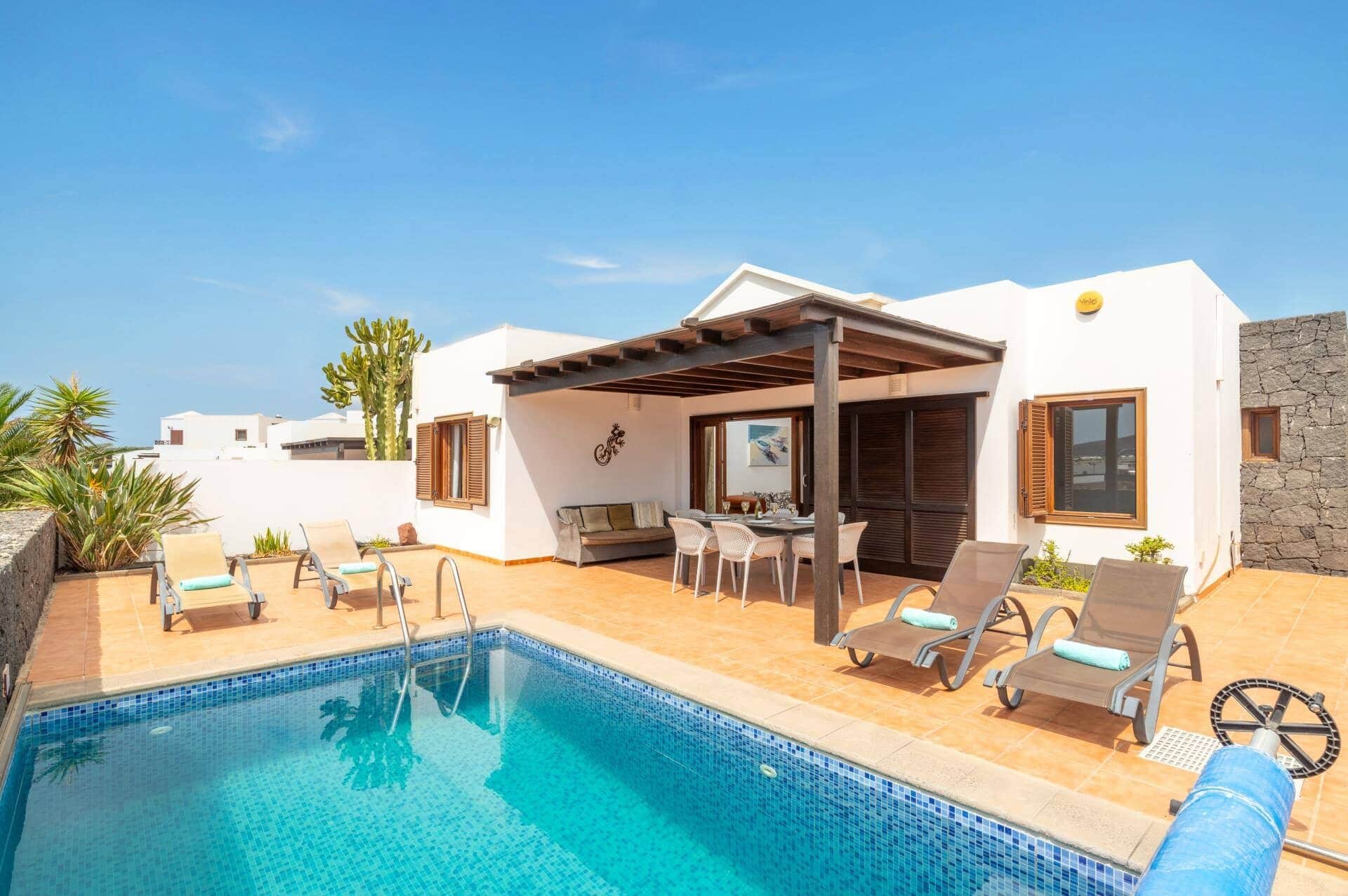 Zona junto a la piscina con piscina, sillas de descanso, un área de estar cubierta y una pared de piedra.