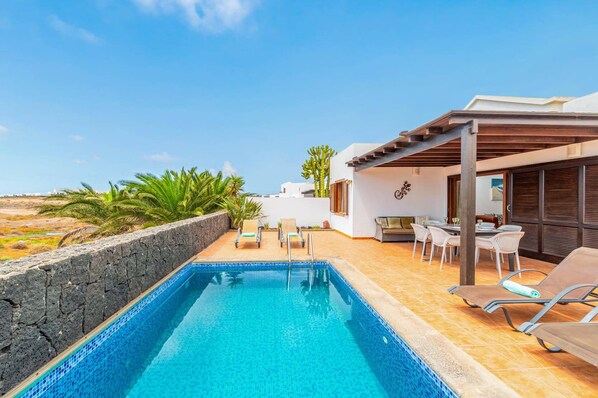 Ein privater Pool mit Steinmauer, Liegestühlen und einer Terrasse mit Blick auf die Landschaft.