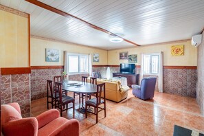 A spacious living area with a dining table, sofas, and a television.