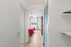 A hallway leading to a bedroom with a bed and a view of the outdoors. - Tropical Paradise at Blue Bay | Pool & Beach Access (Willemstad)
