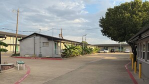 Vista de la calle con una hilera de edificios de una planta, un hidrante y un banco.