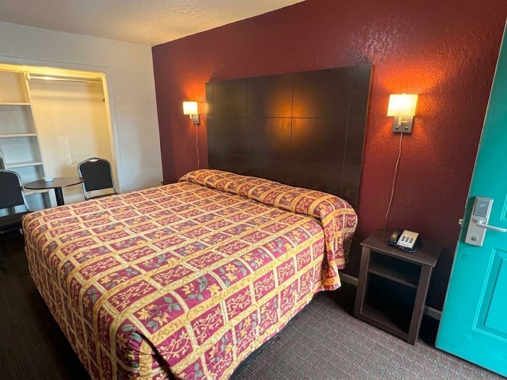 A hotel room with a large bed, a desk, and a chair.