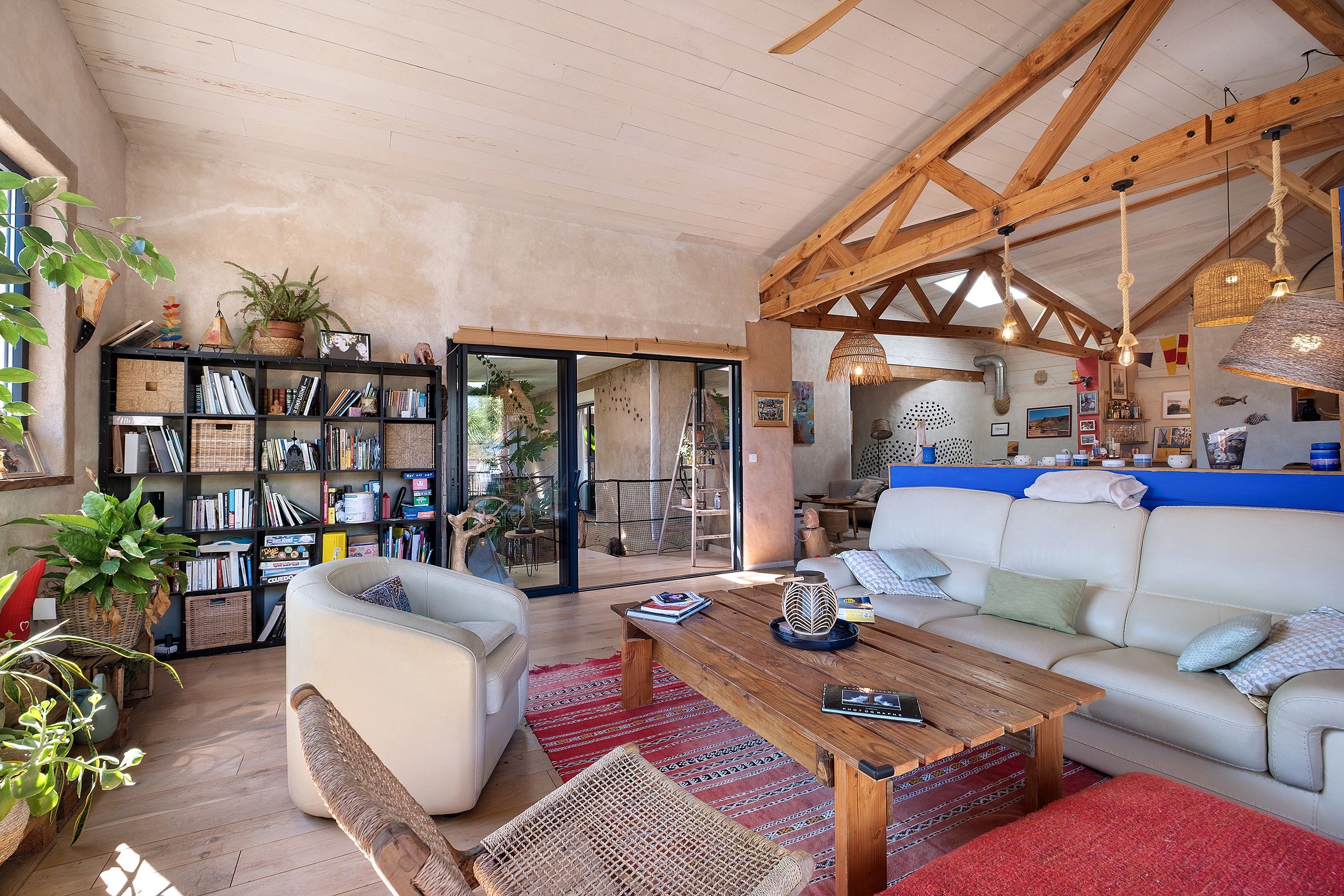 A spacious living area with a white sofa, a wooden coffee table, and a bookshelf filled with books and decorative items.