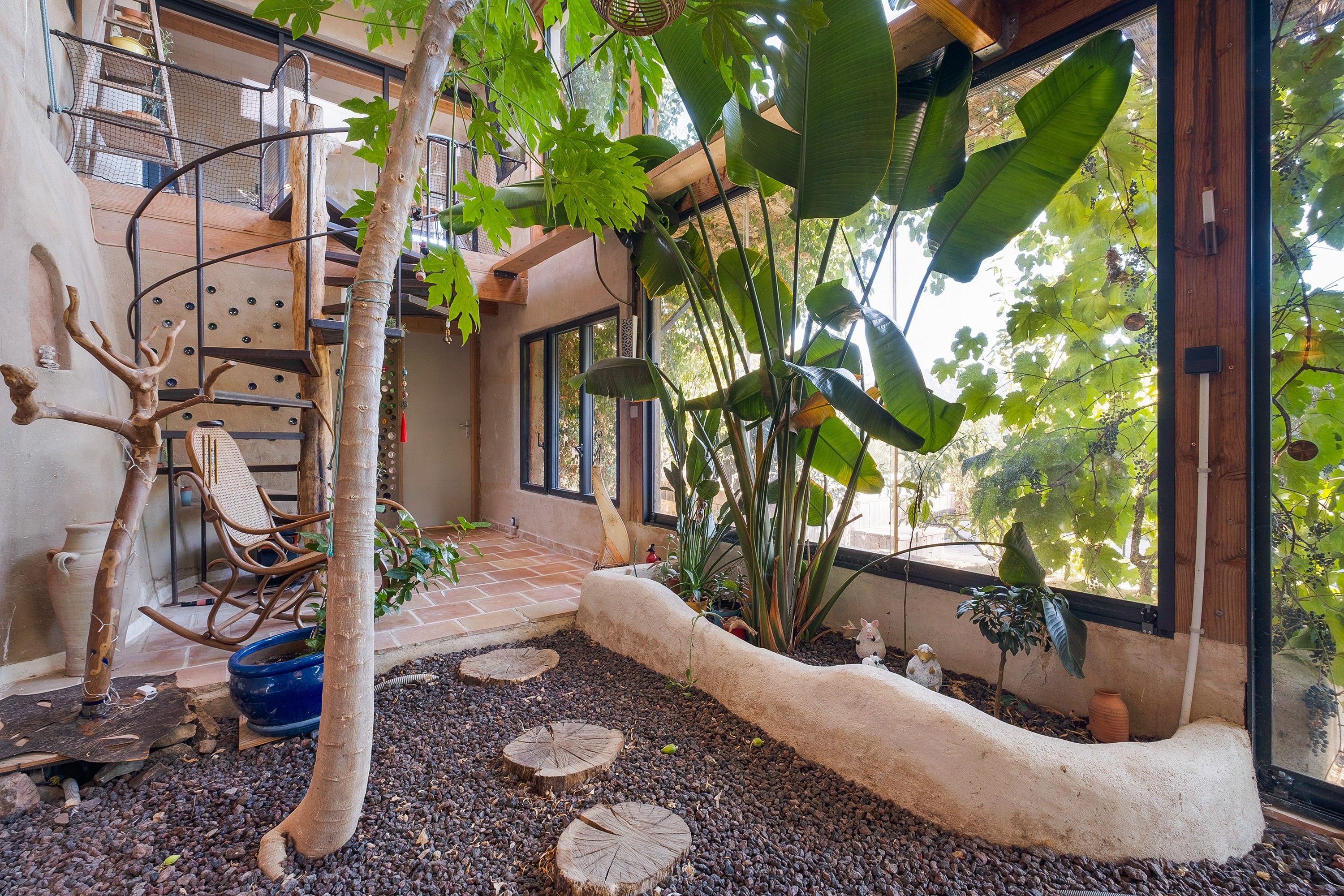 Un jardin intérieur accueillant, agrémenté d’une structure d’escalade en bois, d’un sentier en pierre et de diverses plantes en pot.