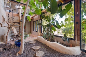 A cozy indoor garden with a wooden climbing structure, a stone pathway, and various potted plants.