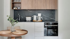 A modern kitchen with a black marble countertop, a coffee maker, a rice cooker, and a dishwasher. - Bank Polski City Center with Parking (Gdynia)