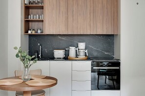 Eine moderne Küche mit einer schwarzen Marmorarbeitsplatte, einer Kaffeemaschine, einem Reiskocher und einem Geschirrspüler.