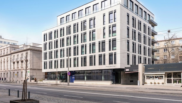 A modern building with a flat facade, multiple windows, and a storefront with signage. - Bank Polski City Center with Parking (Gdynia)