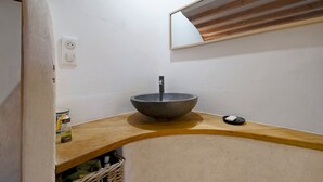 Un baño con lavamanos sobre encimera, un espejo y una encimera de madera.