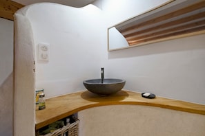 Ein Badezimmer mit einem Aufsatzwaschbecken, einem Spiegel und einer Holzausziehtafel.