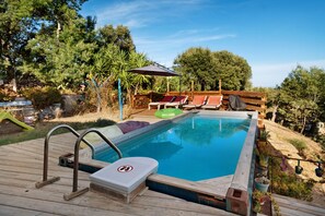Ein Schwimmbecken mit Holzterrasse, Liegestühlen und einem Schild, das das Springen verbietet.