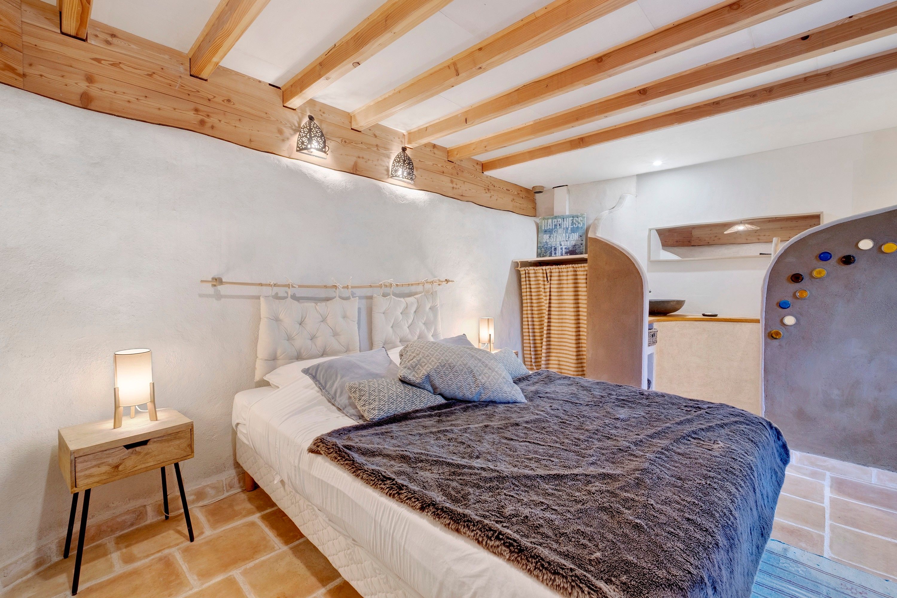 Une chambre à coucher avec un lit, une table de chevet et une lampe fixée au mur.