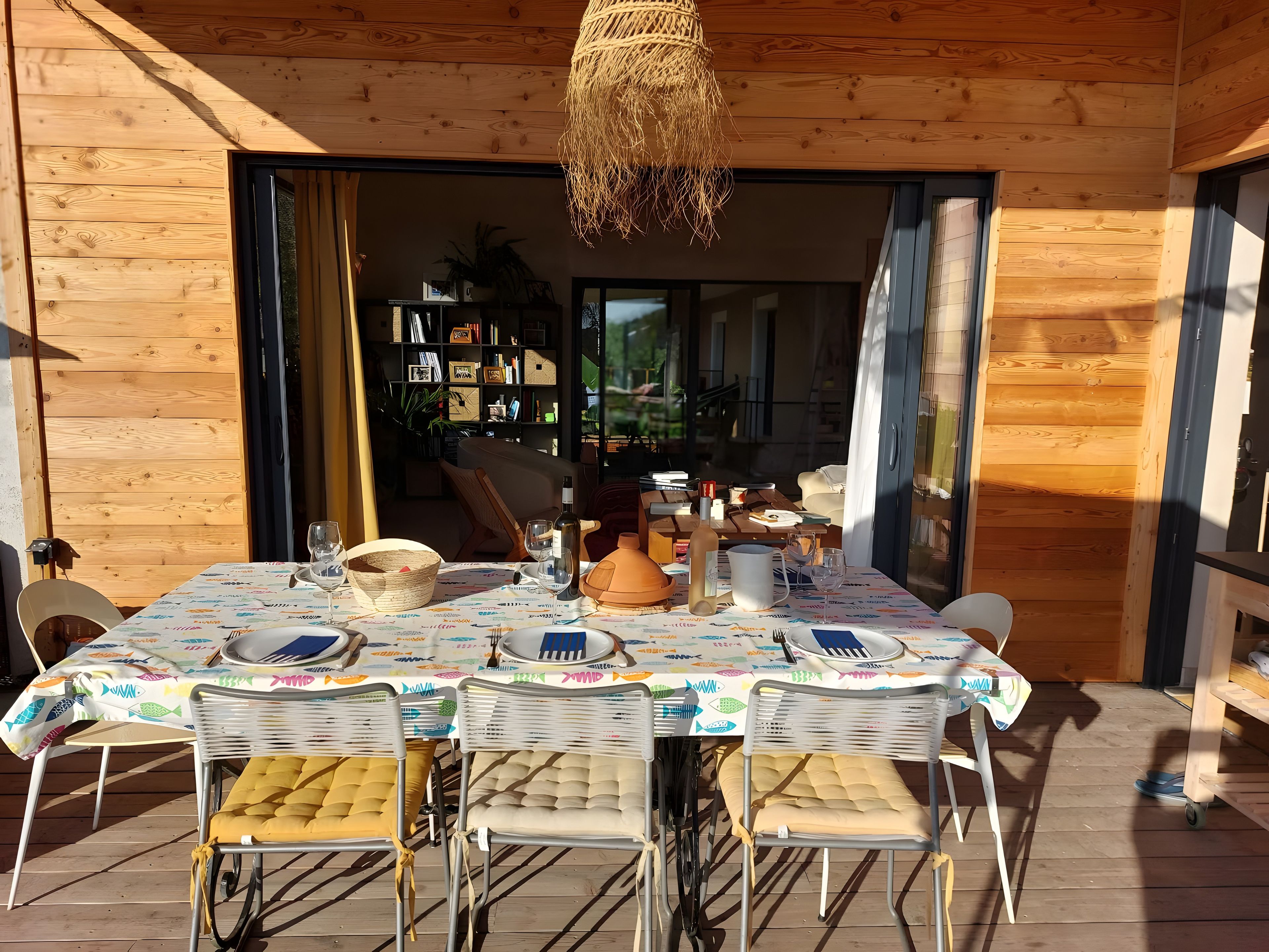 Une cabane en bois avec un coin repas comprenant une table dressée pour deux personnes, des chaises et un luminaire suspendu.