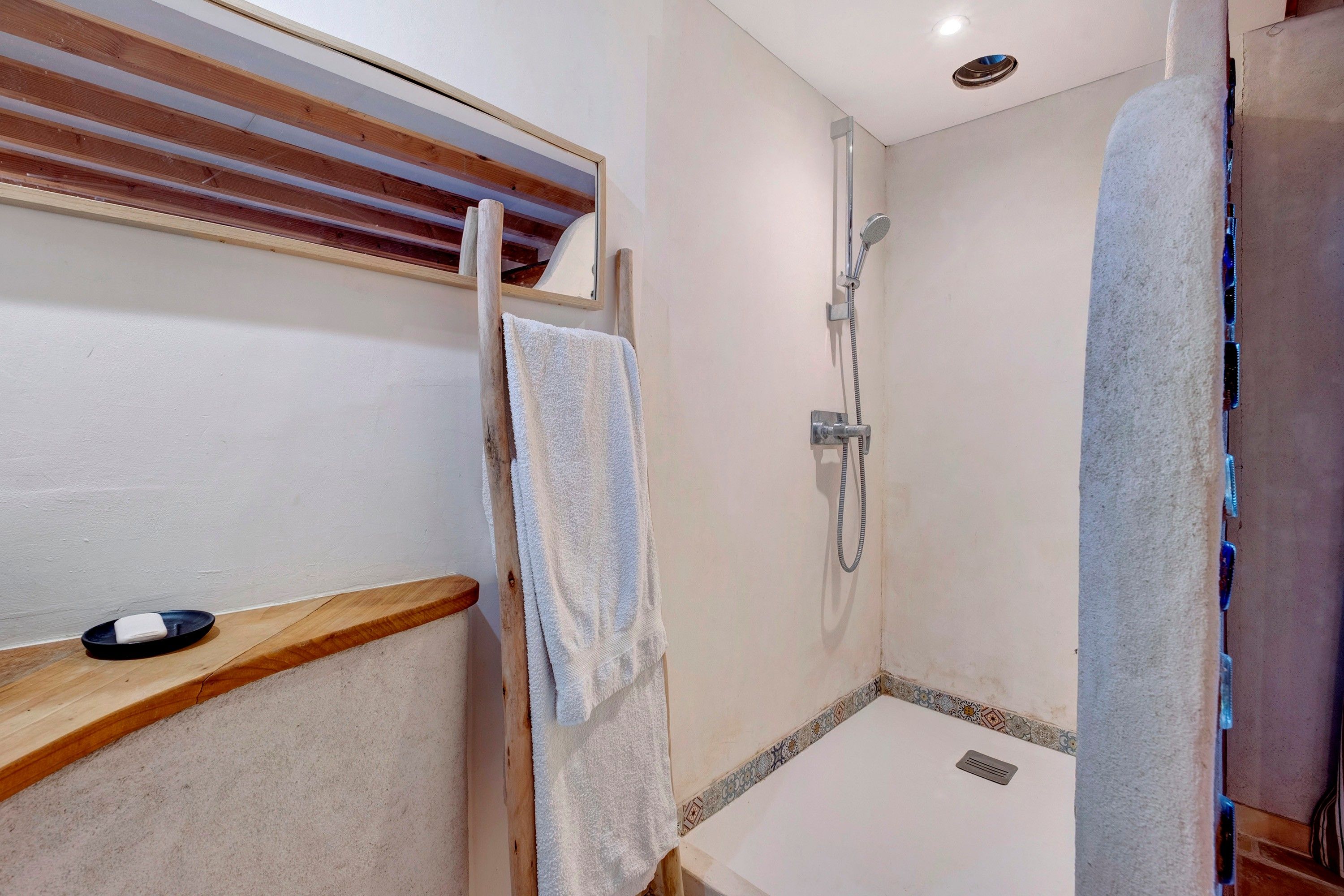 Un espace douche équipé d’un pommeau de douche à main, d’un porte-serviettes et d’une petite étagère.