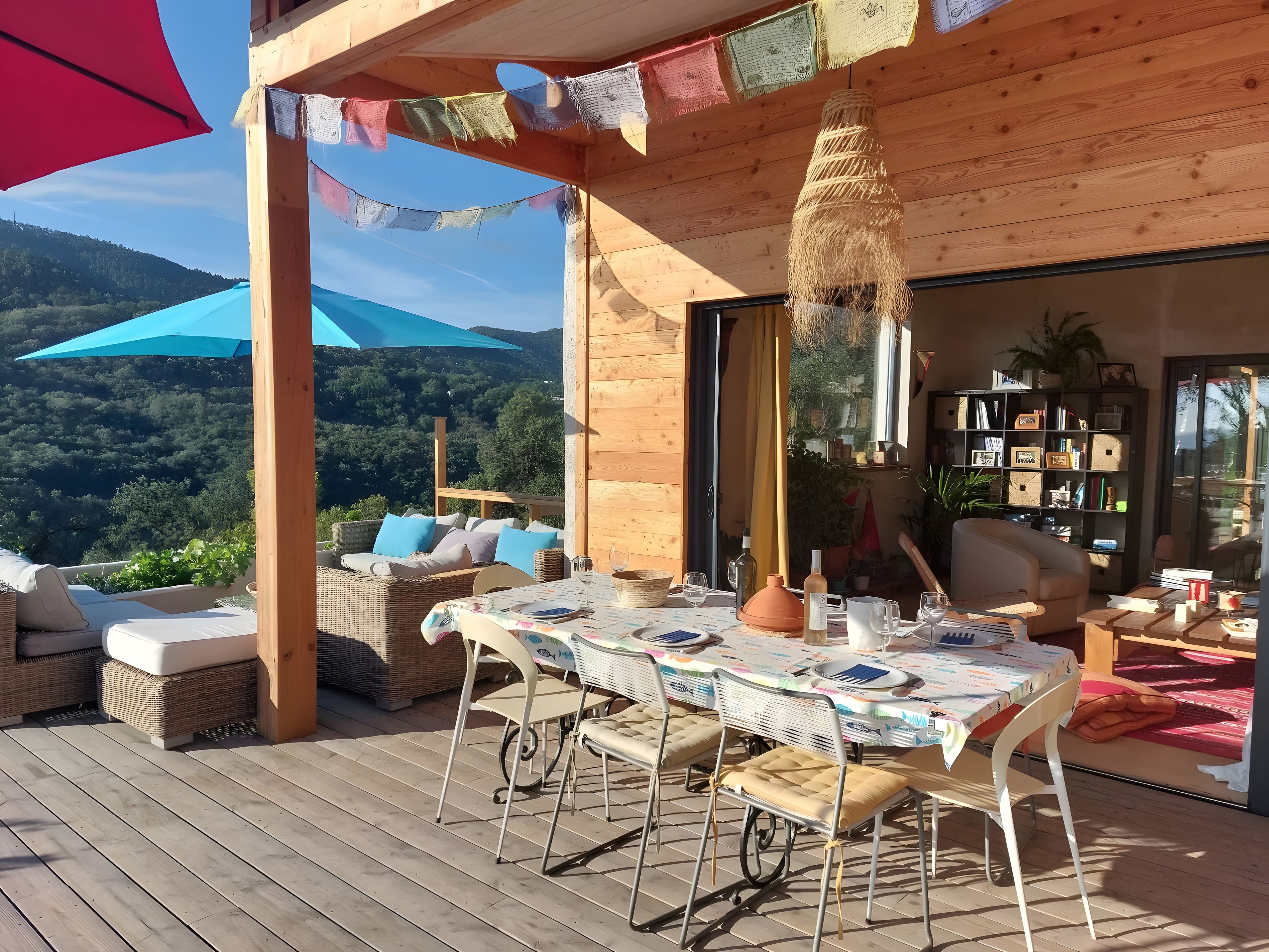 Une terrasse en bois avec une table dressée pour le repas, entourée de meubles et de coussins en osier.