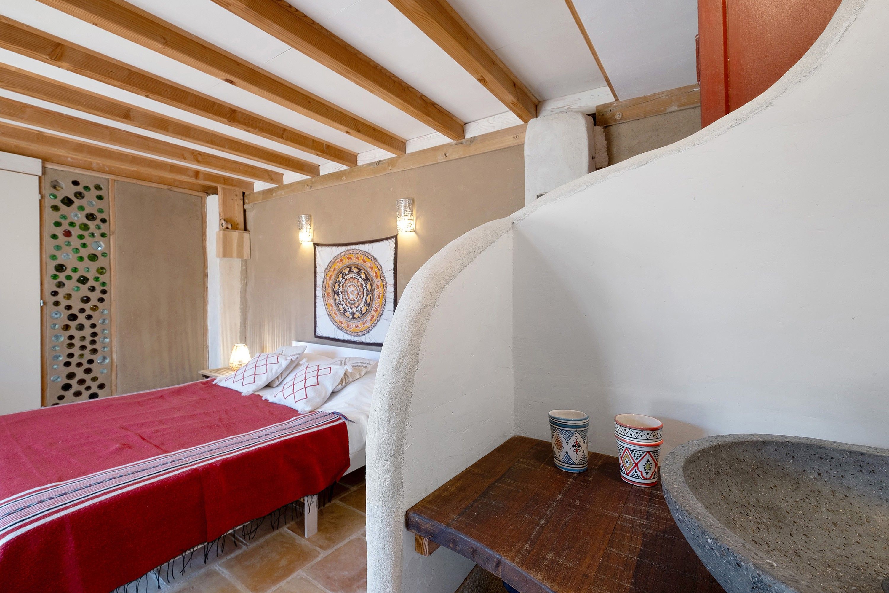 Ein Schlafzimmer mit einem Bett, einem Nachttisch, einer Wandteppich und einem Steingefäß.