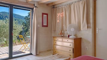 Een slaapkamer met een schuifglasdeur naar een buitenruimte, een houten dressoir, een bed en een ventilator bevestigd aan de muur.