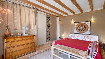 Een slaapkamer met een houten bed, een bankje, een dressoir en een wand met een wandtapijt.