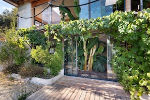A modern house with a wooden deck, a glass conservatory, and a variety of plants including grapevines. - Bed and Breakfast 'Marsaou' with Mountain View, Shared Terrace and Wi-Fi (Les Adrets-de-l'Estérel)