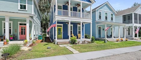 A residential area with two-story houses, each with a front porch and American flags.