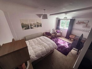 Ein Schlafzimmer mit einem Bett, einem Sessel, einem Schreibtisch und einer Heizung.