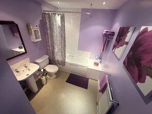 Ein Badezimmer mit Toilette, Waschbecken, Badewanne und Duschvorhang.