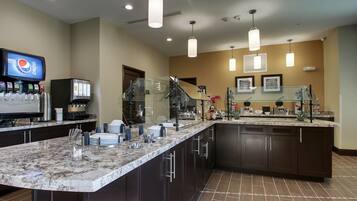 A modern kitchen with a granite countertop, dark cabinets, and a built-in refrigerator.