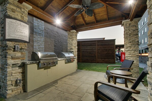 An outdoor patio with a stone wall, a grill station, and seating.