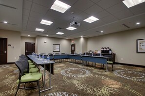 A conference room with a long table, chairs, water bottles, a projector, and a coffee station.