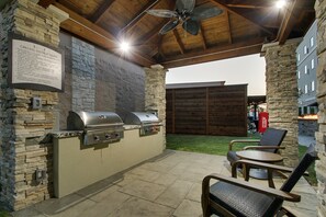 An outdoor patio with a stone wall, a grill station, and seating.