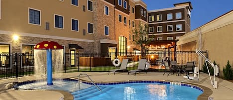 A hotel pool area with a water feature and lounge chairs.