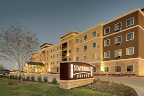 A Staybridge Suites hotel with a sign, multiple floors, and a parking lot.