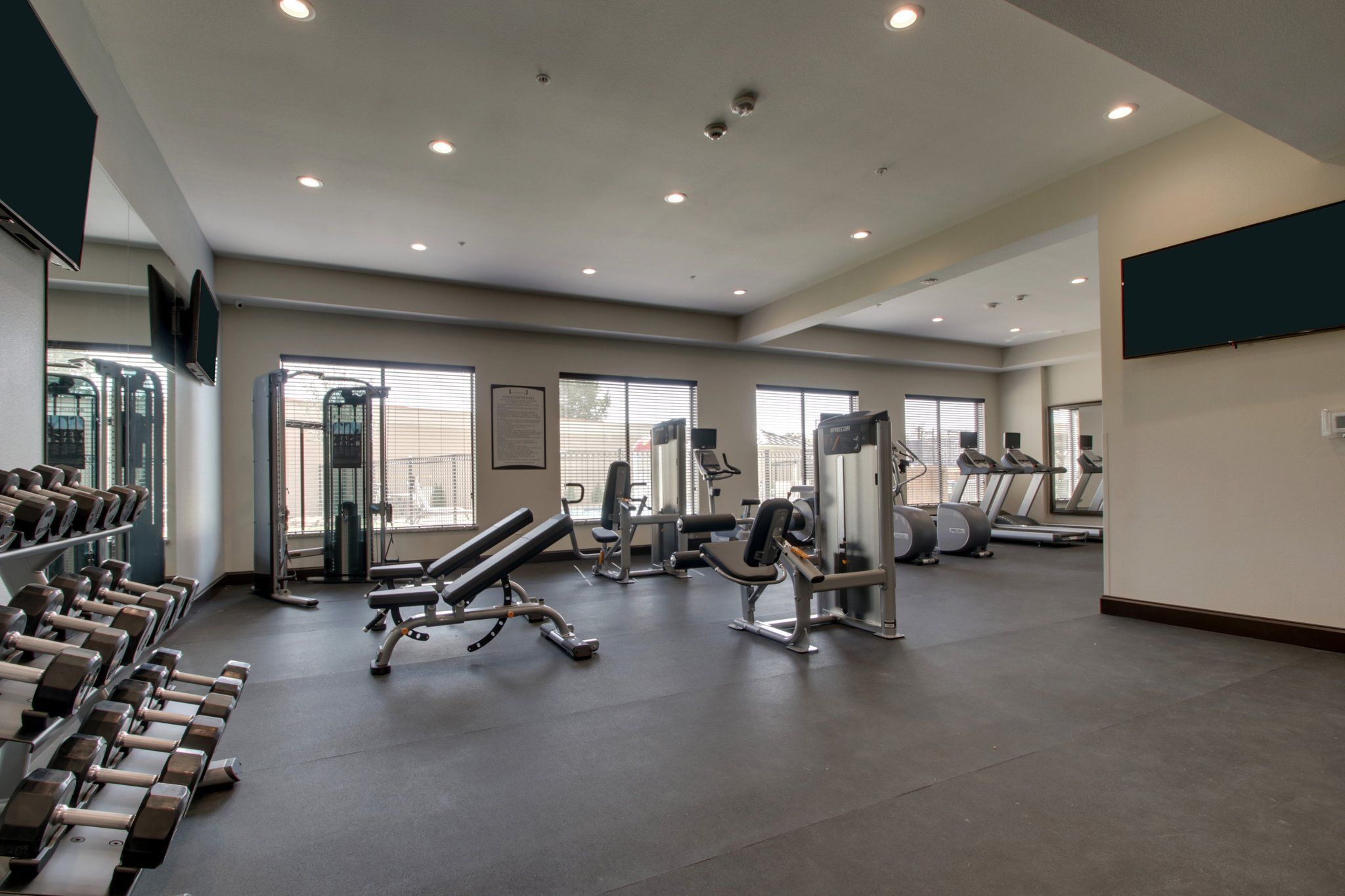 A gym with treadmills, dumbbells, and weight machines.