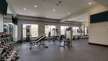 A gym with treadmills, dumbbells, and weight machines.