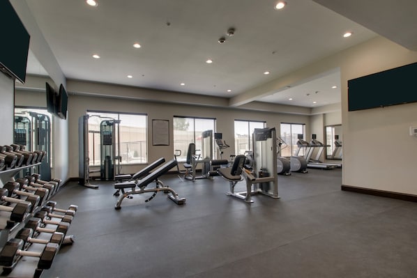 A gym with treadmills, dumbbells, and weight machines.
